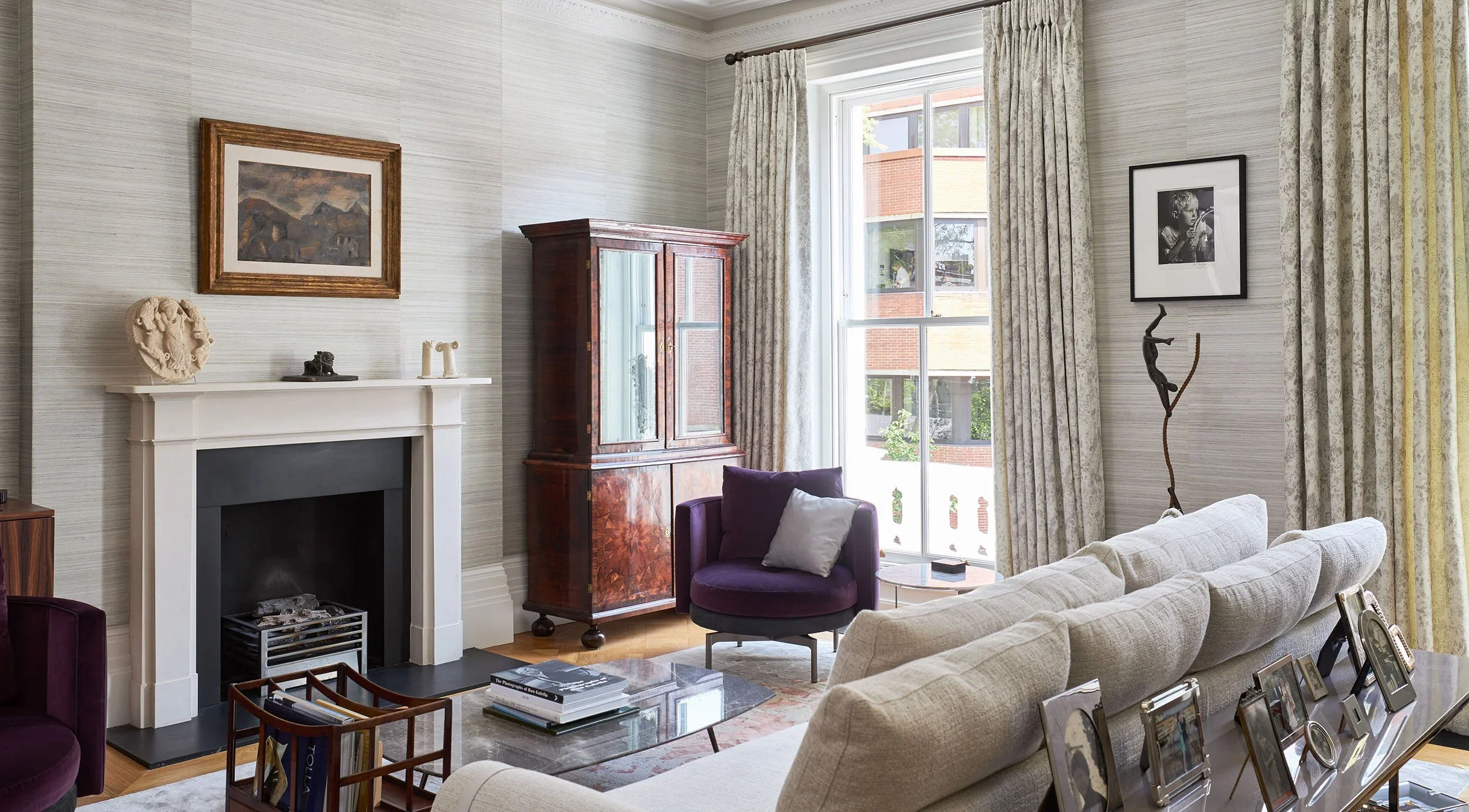 Living room interior of Kensington TownHouse by Bolton Chalklin Architects featuring a fireplace, textured wallpaper, and purple velvet armchair.