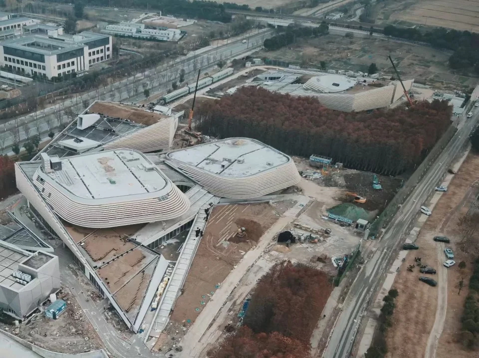 Aerial construction view of organic multi-lobed buildings with banded facades integrated into a landscape by 得当设计.