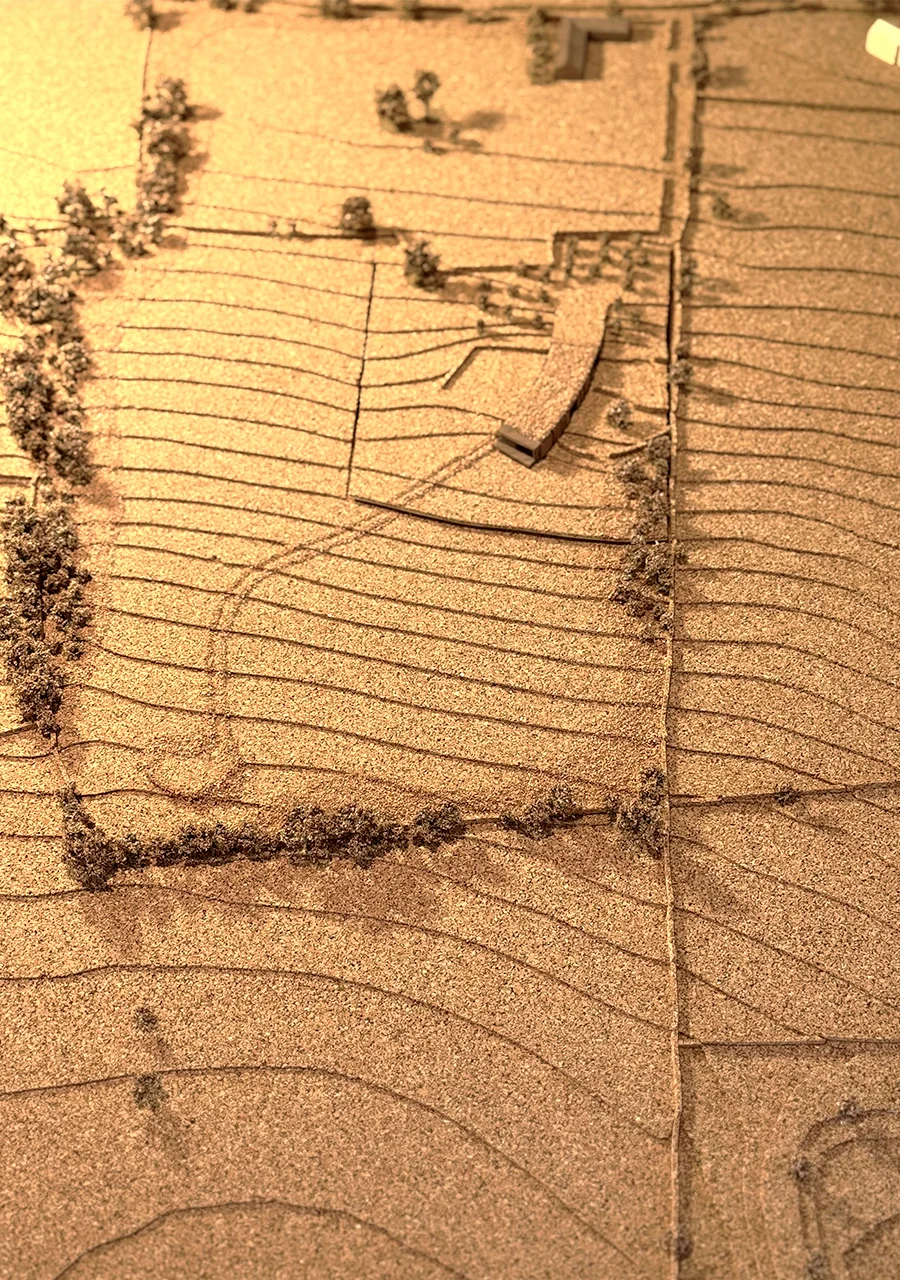 Physical terrain model by PAD studio showing a curving building embedded in contoured agricultural land.