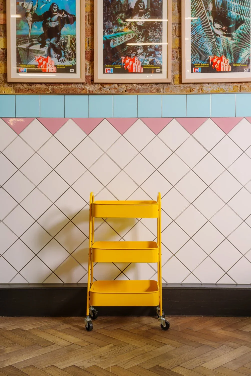 Interior detail of Plaza Khao Gaeng in Borough by Applied Studio featuring a yellow utility cart against patterned ceramic tiles and exposed brick.