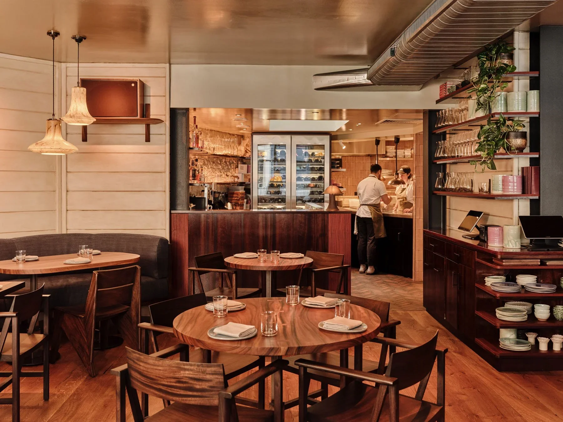 Interior view of AngloThai restaurant in Marylebone by Applied Studio, featuring dark wood dining tables and a view into the open kitchen.