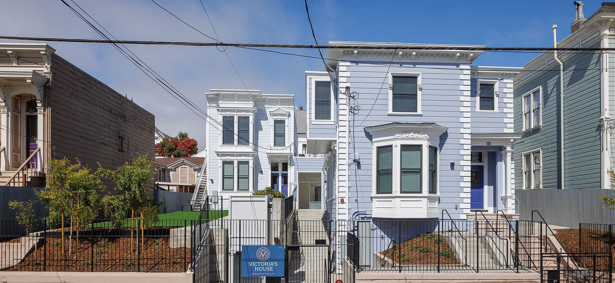 Exterior street view of Victoria’s House Transitional Housing by OpenScope Studio showing historic pastel blue Victorian architecture and site layout.
