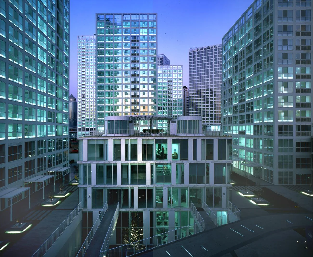 Jian Wai SOHO in Beijing by Riken Yamamoto, featuring glowing gridded towers surrounding a central pavilion at dusk.