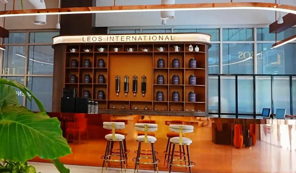 Interior shot of Leos International reception and tea counter featuring custom shelving, copper finishes, and upholstered bar stools.