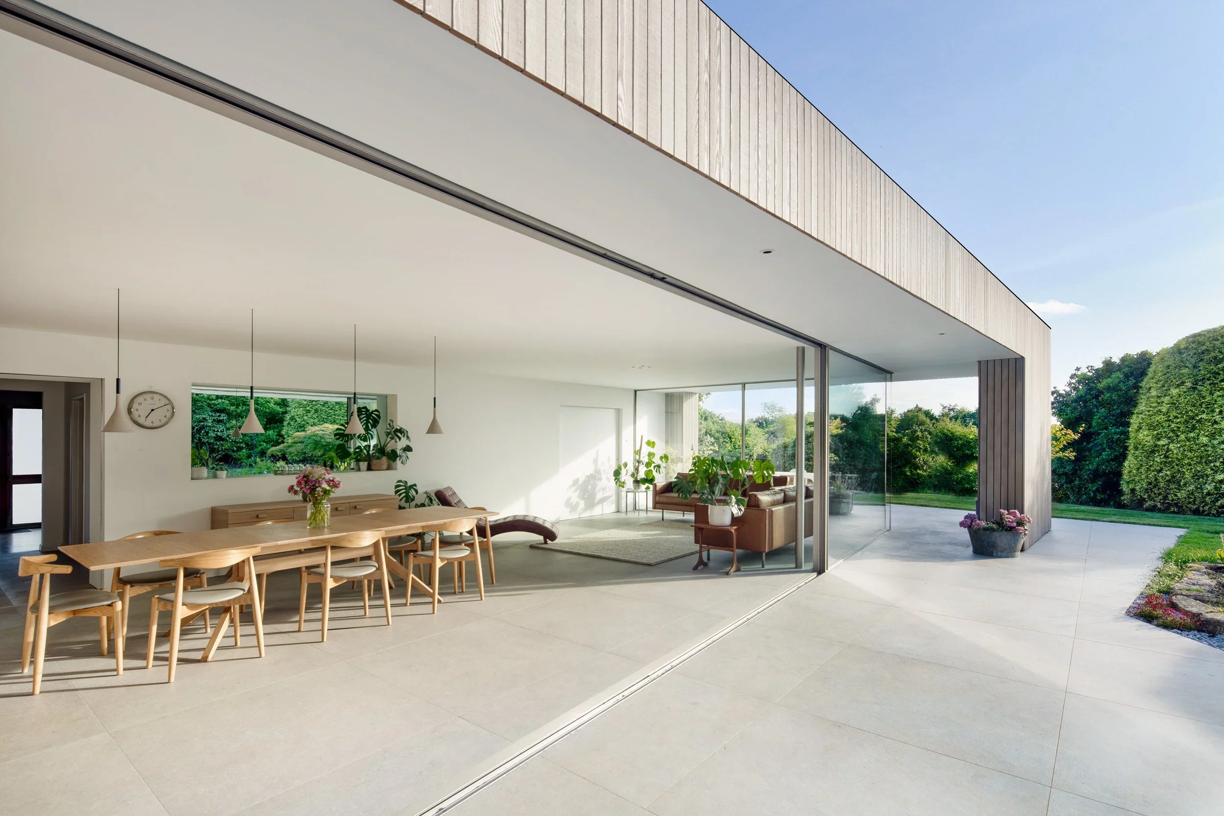 Indoor-outdoor living space with large sliding glass doors and timber cladding by AR Design Studio.