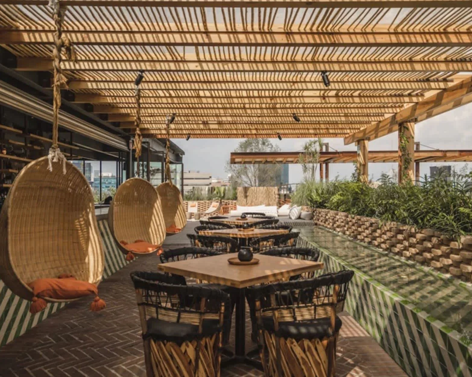 Rooftop terrace lounge with timber pergola and hanging wicker chairs by Studio Antoine.
