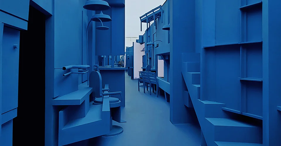 Monochrome deep blue exhibition installation space featuring stylized furniture, stairs, and objects by PILLS.