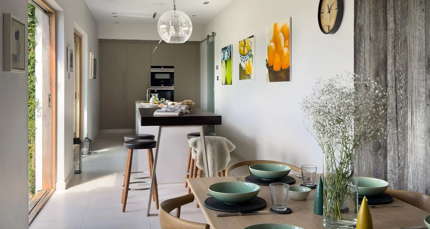 Long open-plan kitchen and dining interior by Hobson's Choice with sliding glass doors and warm timber details.