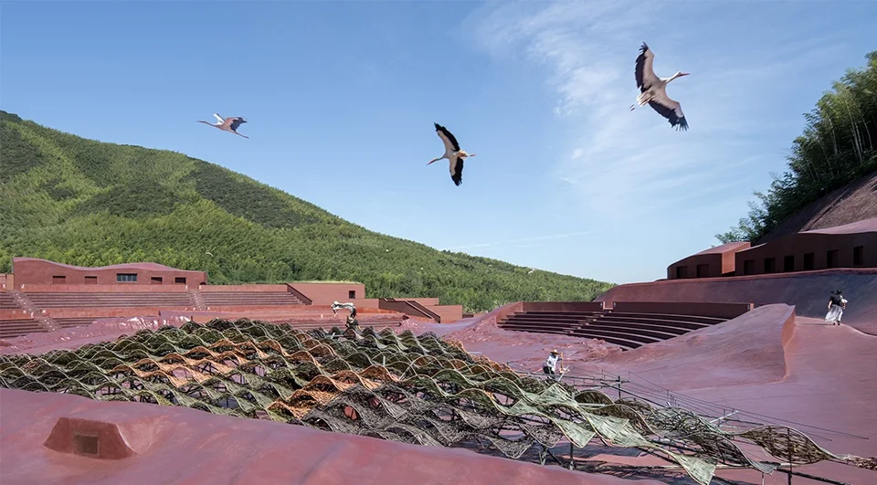 Aerial view of a large reddish-brown terraced amphitheater landscape with undulating woven bamboo shades and flying birds by goa大象设计.