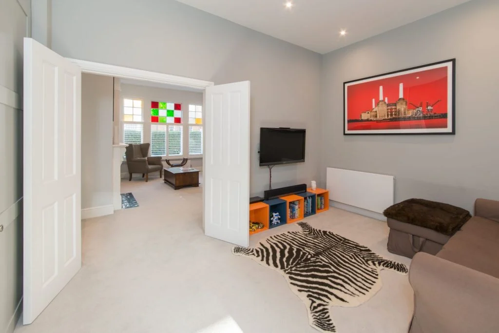 Interior view of a residential sitting room connected via double doors to a front parlor by Atelierdb Architects.