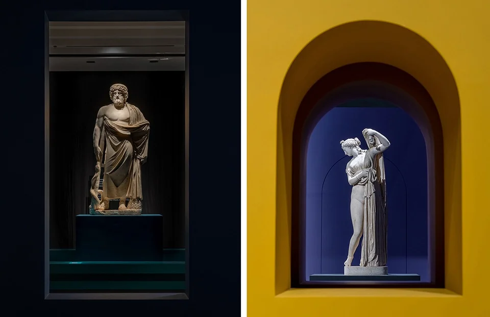 Exhibition interior by Cibic Workshop featuring classical statues displayed in deep color-blocked niches.