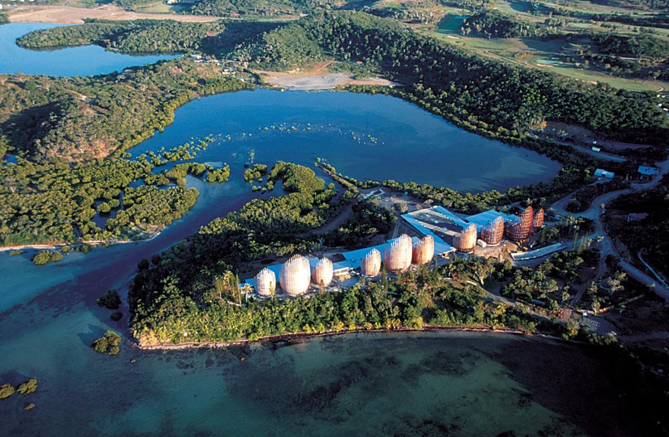 Aerial view of the Tjibaou Cultural Centre's curved wooden pavilions on a forested peninsula by Renzo Piano.