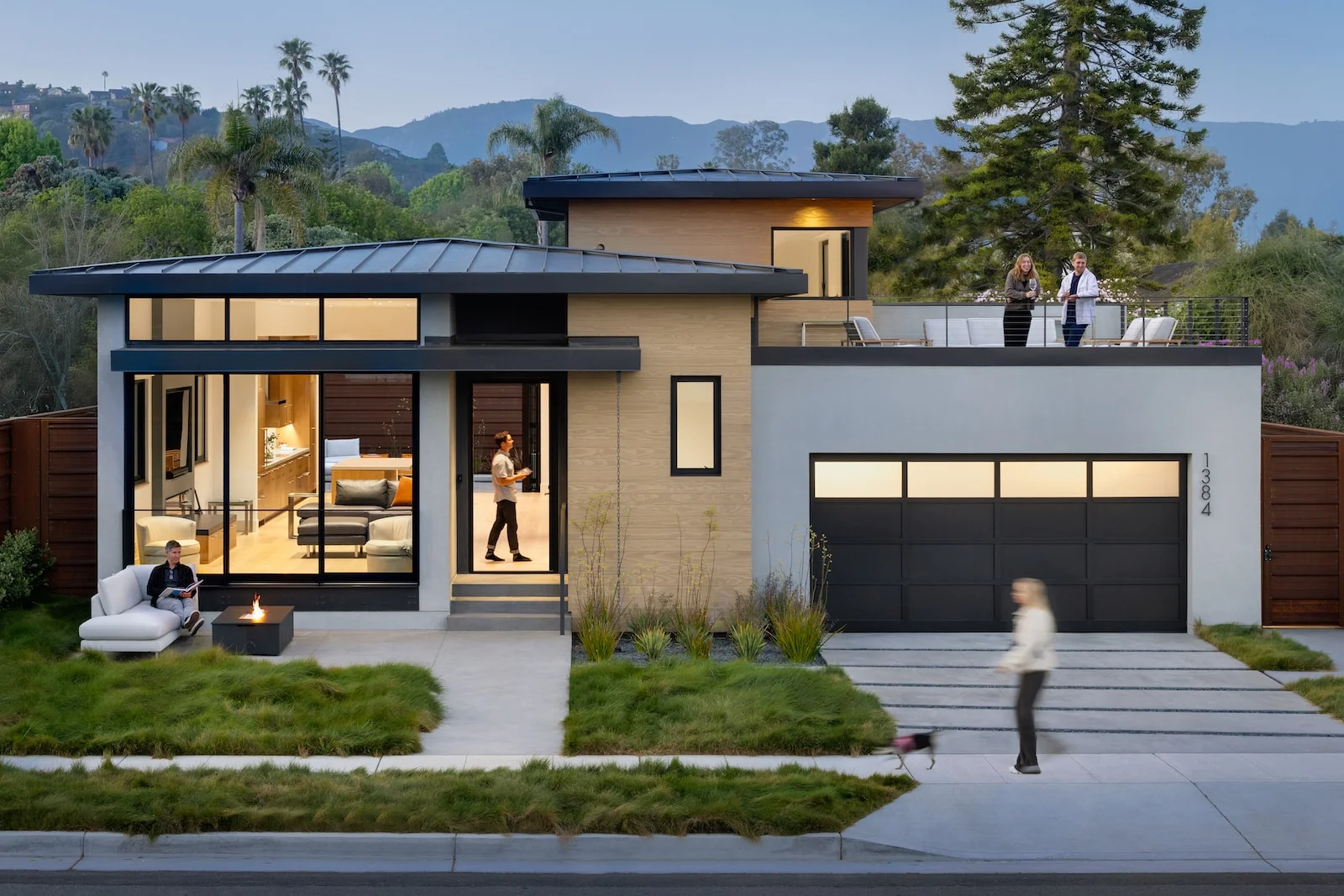 Modern coastal two-story home with flat metal roofs, large glass windows, wood siding, and rooftop deck by Blackbird Architects.