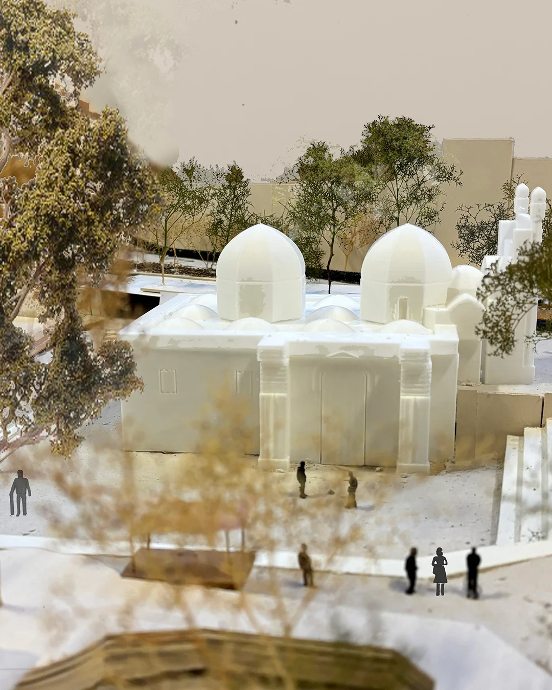 Physical architectural model of a domed building with flanking trees and scale figures.