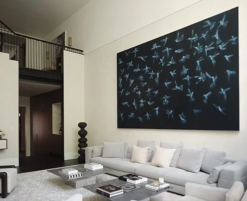 Double-height living room featuring a massive dark artwork and mezzanine bridge by Leroy Street Studio.