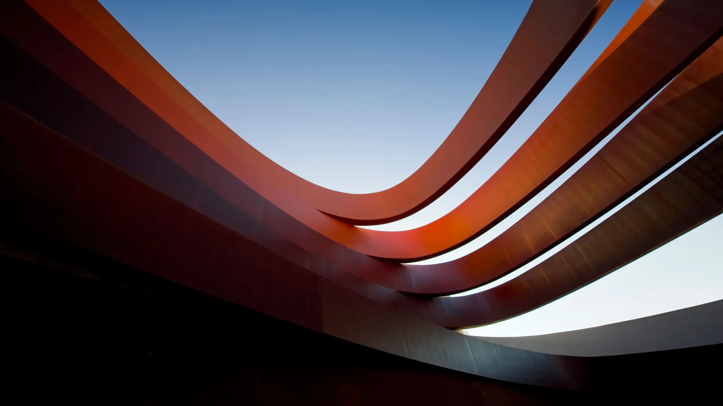 Curved sweeping steel ribbons by Ron Arad Studio framing the sky.