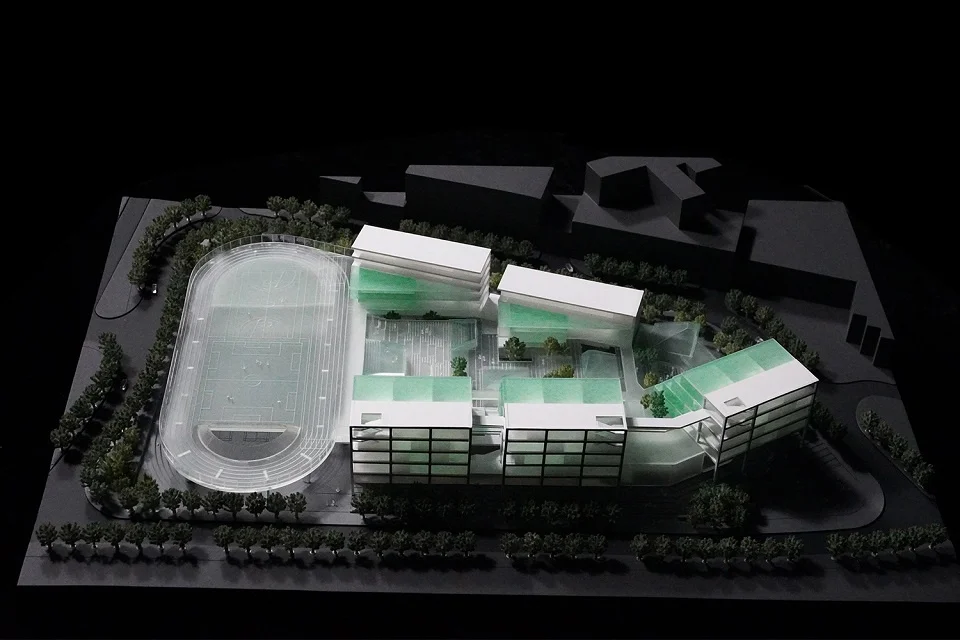 Physical architectural model of Lishan Primary School by MLA+ showing a running track, courtyard buildings, and green roofs on a black base.