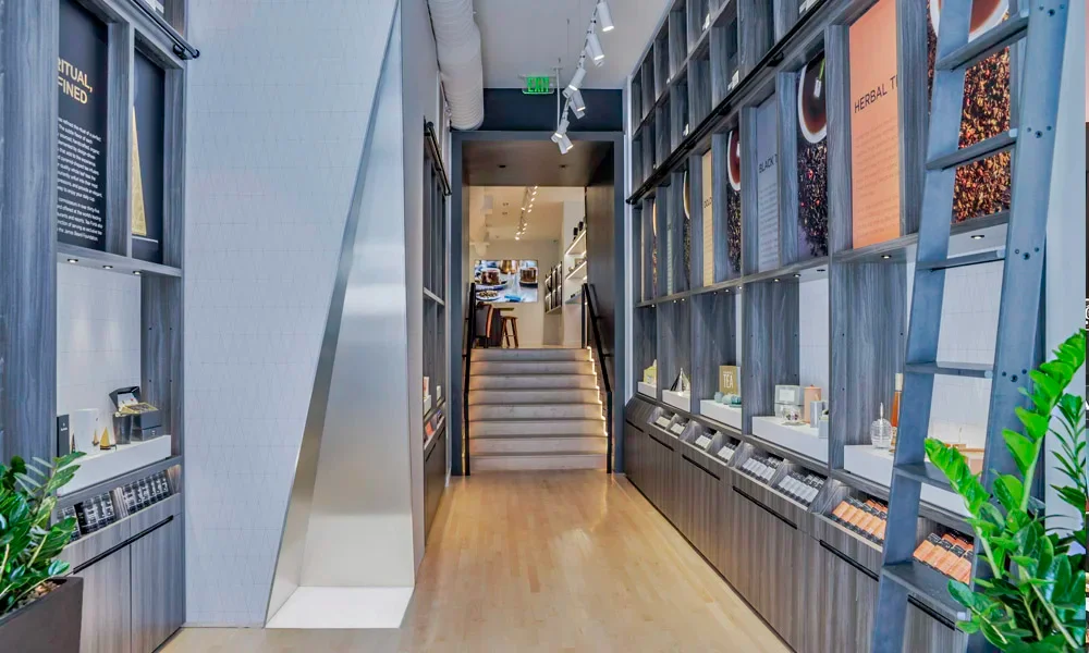 Interior retail space for Tea Forte on Newbury Street by O'Neil Langan Architects, featuring tall wood-grained shelving units and a rolling ladder.