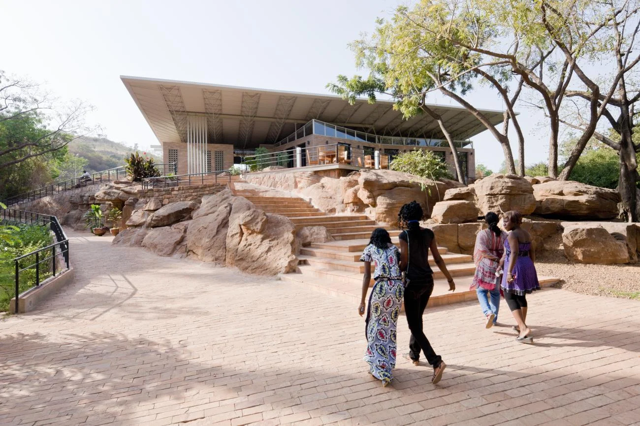 National Park of Mali pavilion by Francis Kéré, featuring a large overhanging roof on a rocky hill.