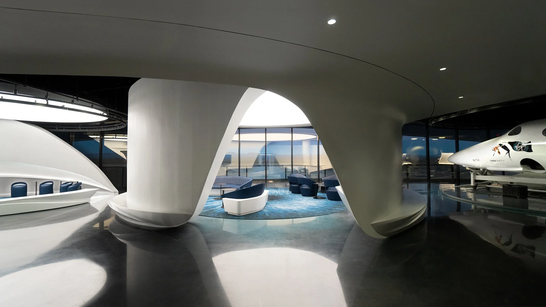 Futuristic corporate interior featuring curved white composite partitions and polished dark floors by Belzberg Architects.