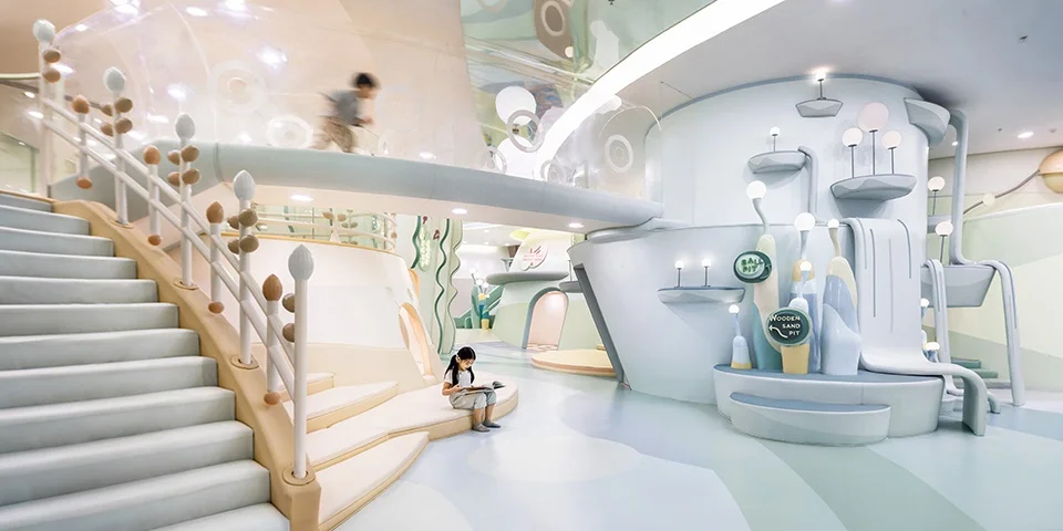 Interior of Meland children's indoor playground in Shanghai by SLT featuring curved forms, pastel colors, stairs, bridges, and play installations.