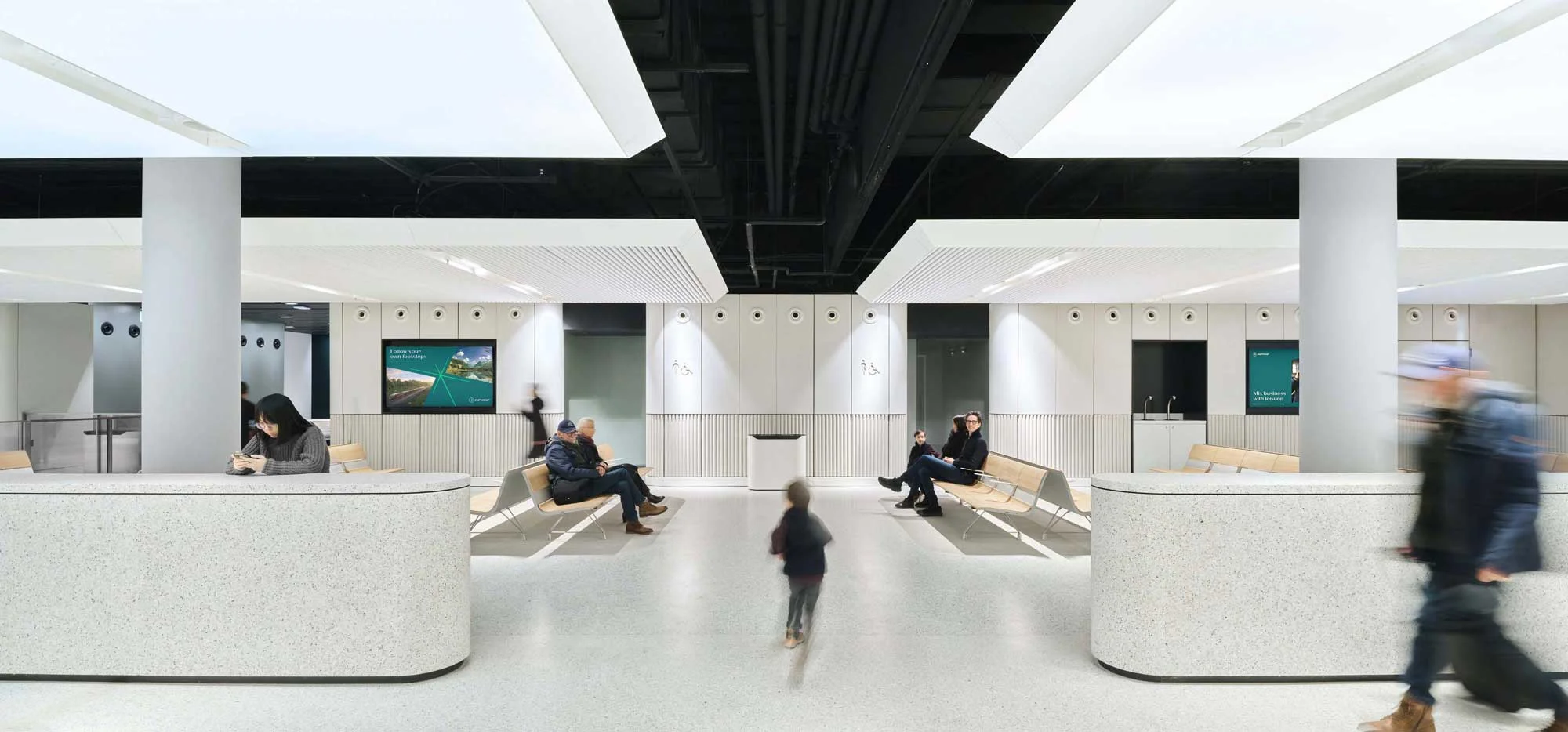 Interior passenger terminal waiting lounge with curved terrazzo counters and recessed luminous ceiling panels by Superimpose Architecture.