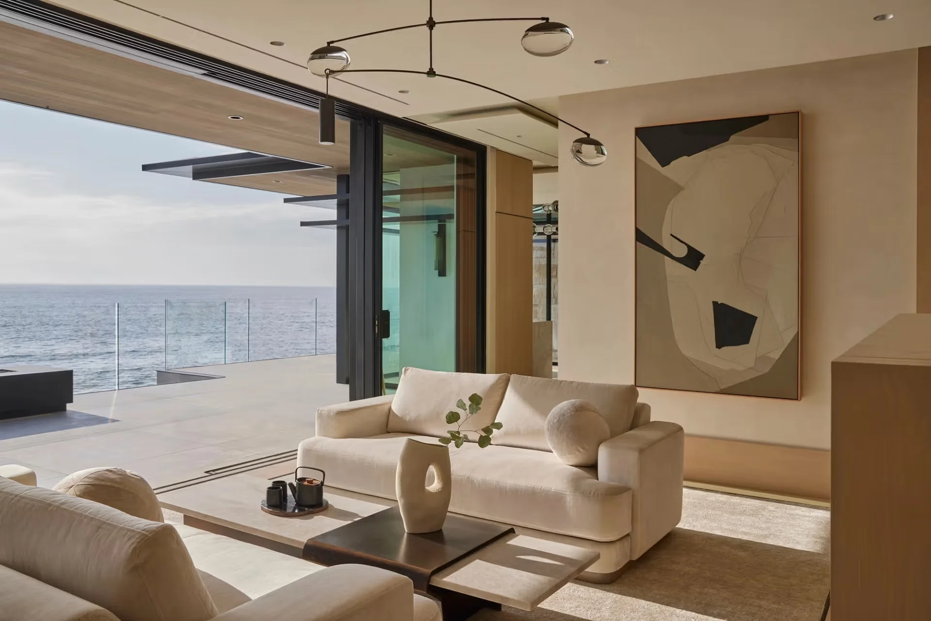 Coastal living room with sliding glass open to ocean view by Brandon Architects.