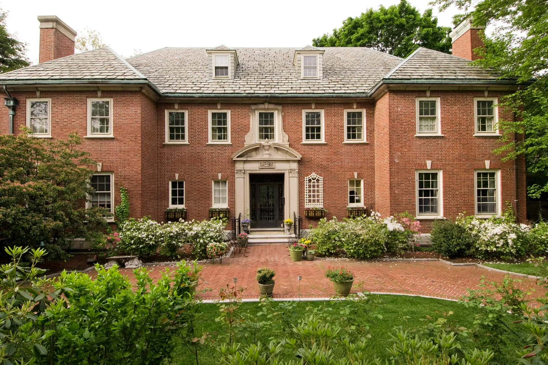 Symmetrical brick Georgian colonial residence exterior with slate roof and formal entry surround.