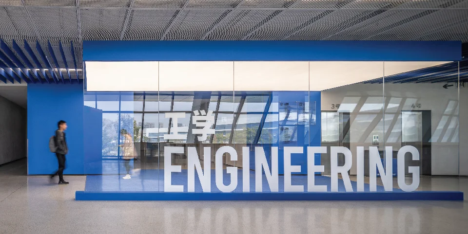 Interior view of an academic lobby with a glazed engineering department enclosure and blue branding by Weico.