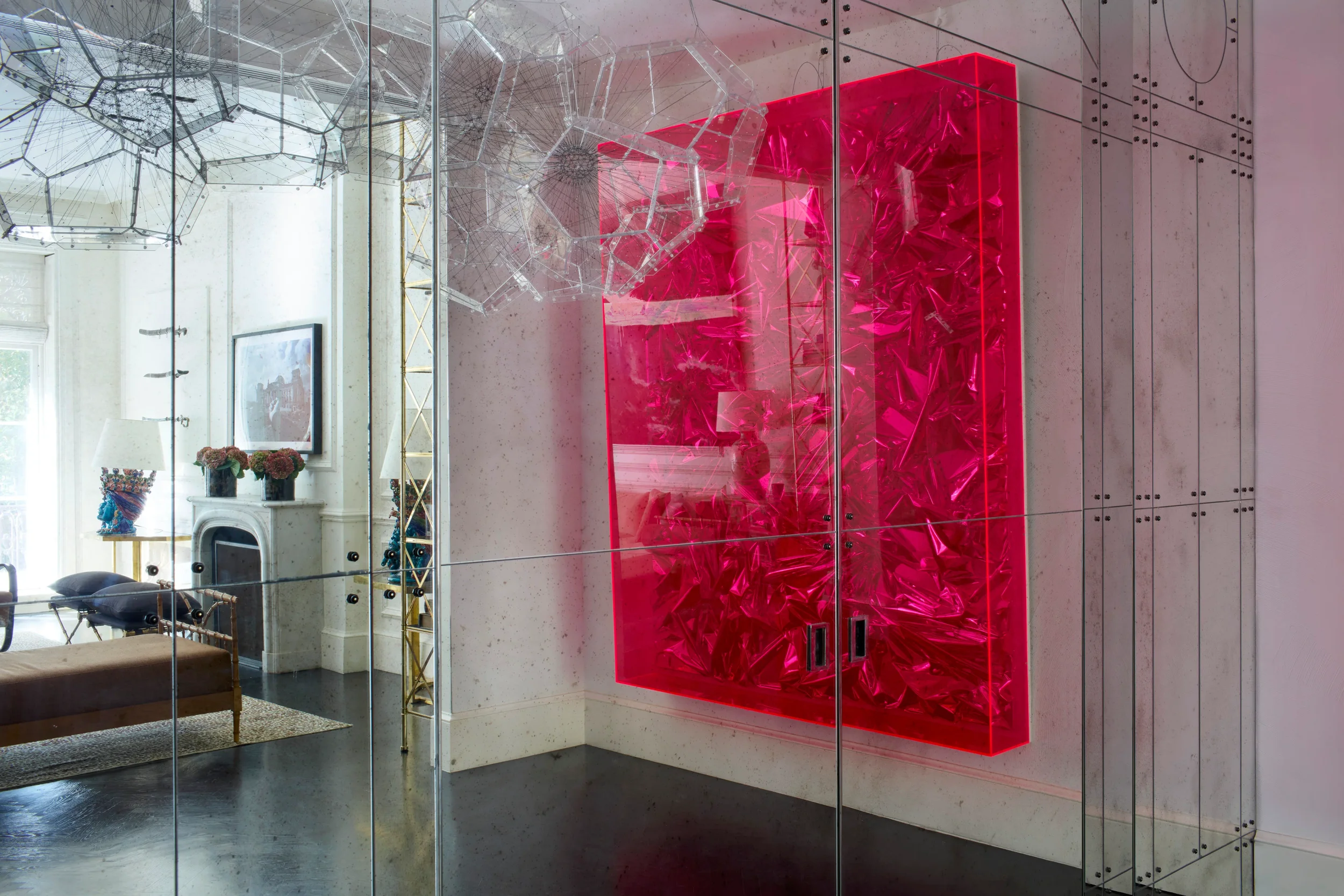 Interior view of a New York apartment by Paolo Moschino featuring a mirrored glass partition and a bright magenta acrylic art display.